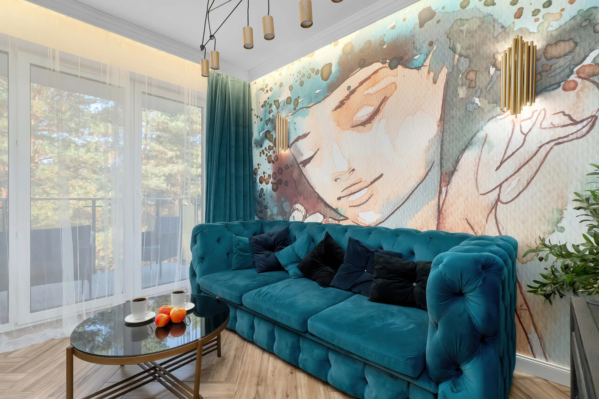 Stylish living room with a teal velvet sofa, colorful mural wall art and large windows.