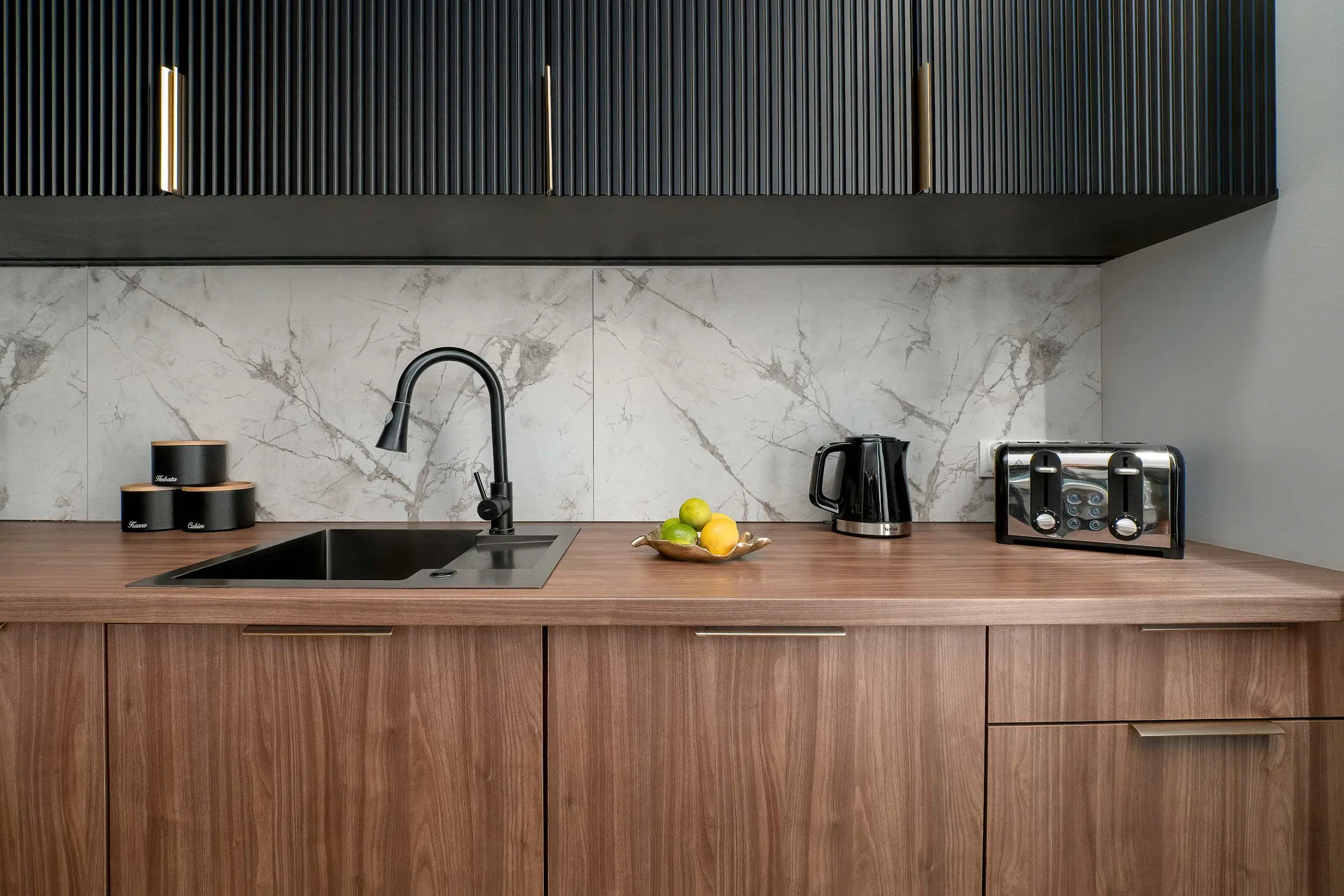 Contemporary kitchenette with wooden lower cabinets, black upper cabinets and a marble-effect backsplash.