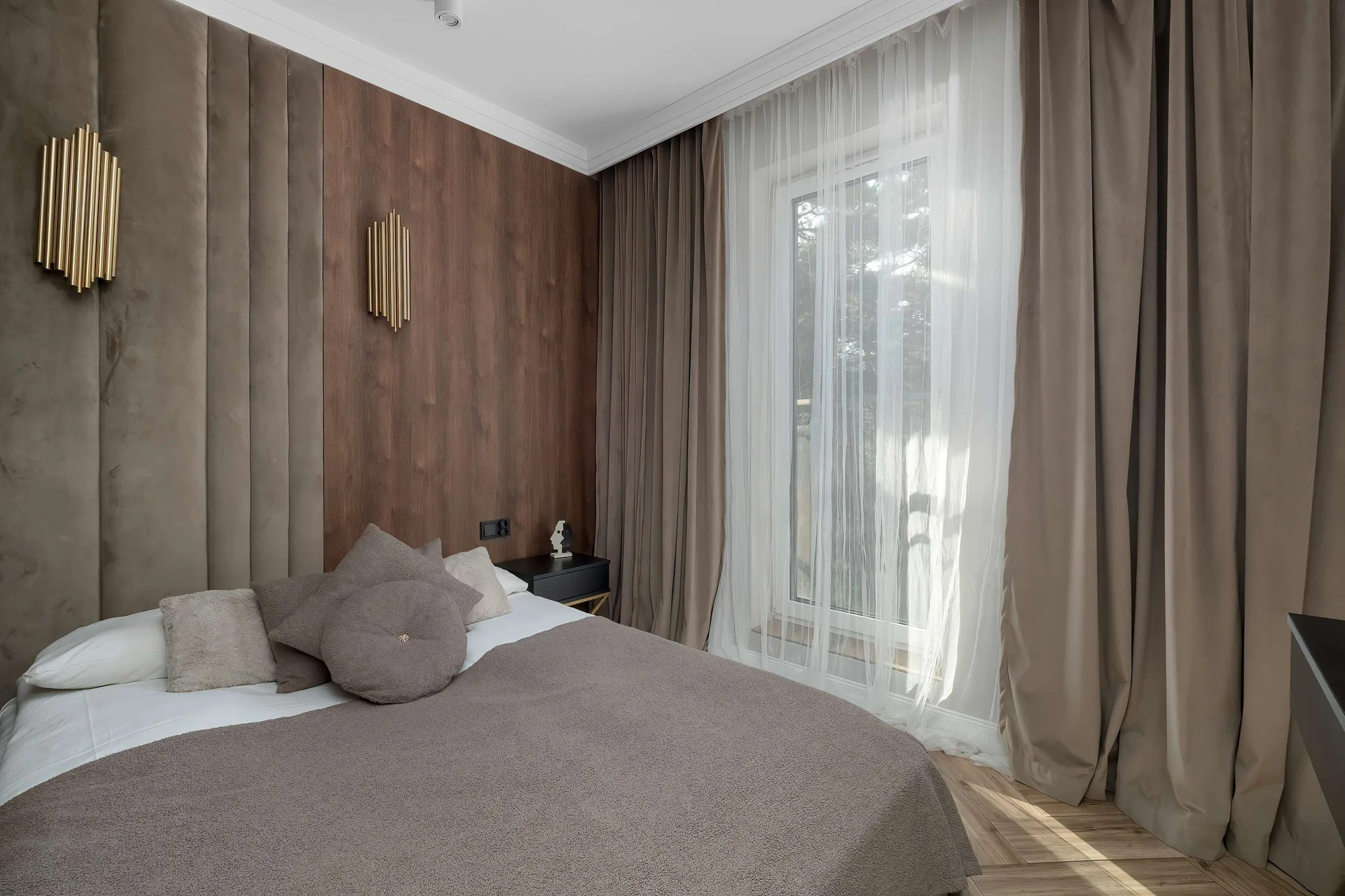Cozy bedroom with a comfortable double bed, warm wood-paneled walls, and elegant bedside lighting.