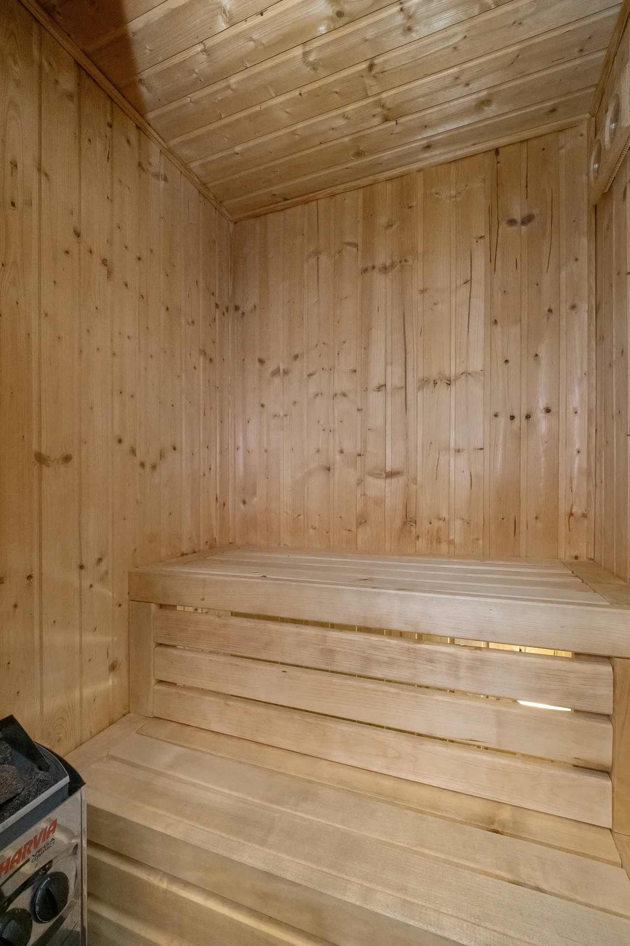 Wooden sauna with natural timber walls and built-in seating.
