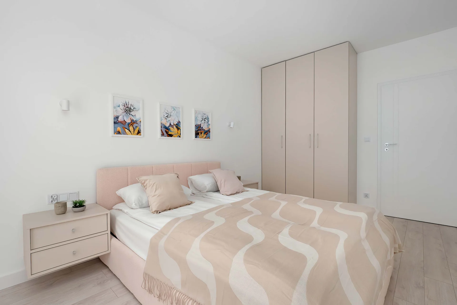 A bright bedroom with a double bed, soft bedding, and a spacious wardrobe.