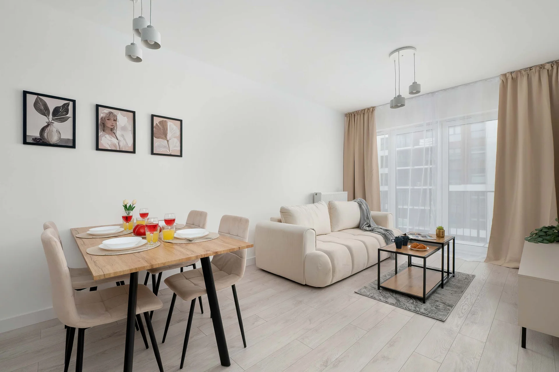 An open-plan living and dining area with a cream sofa, a wooden dining table, and decorative wall art.