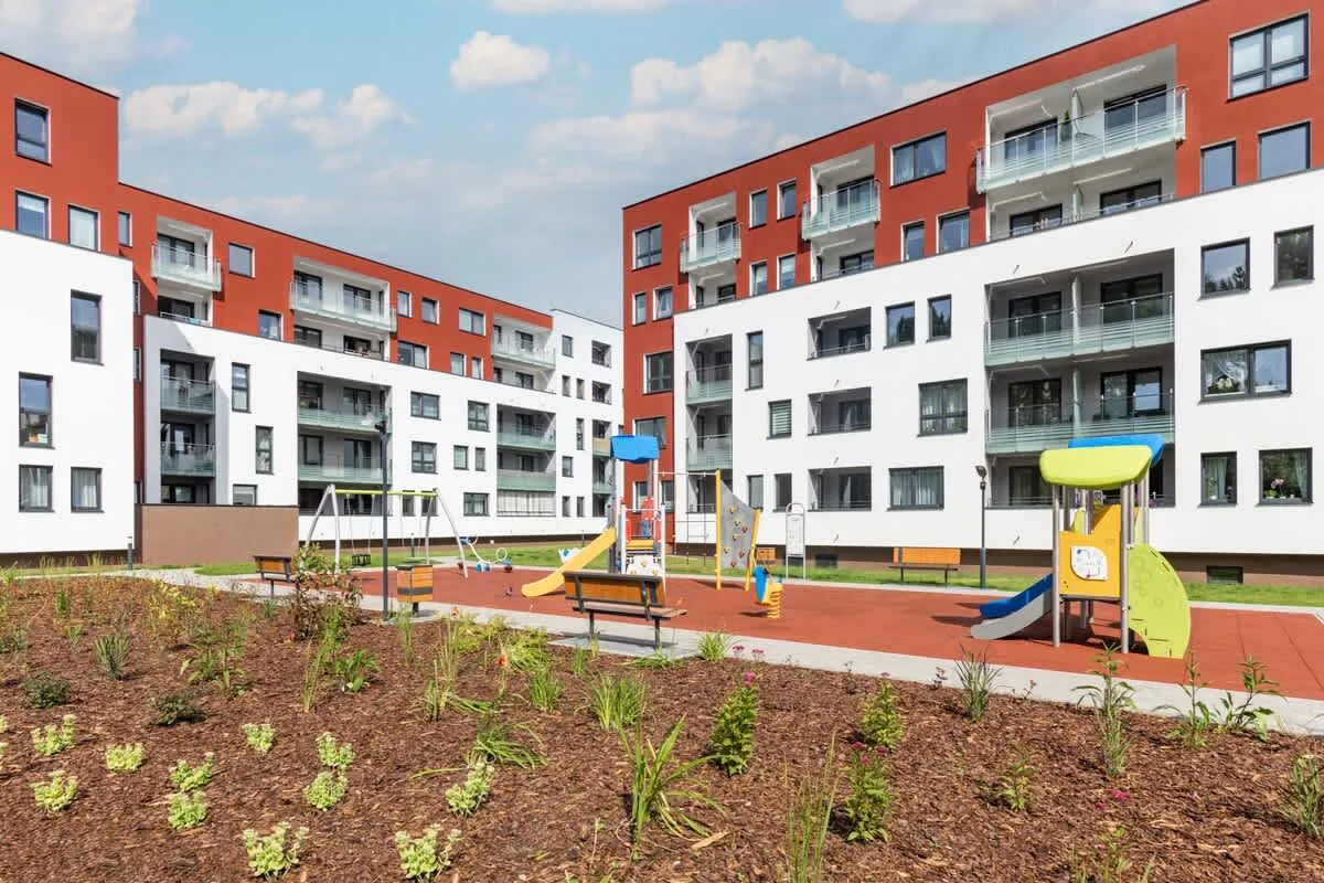 An exterior view of the residential complex with red and white facades and a playground.