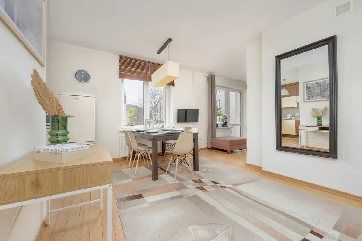 A well-lit open-concept dining and living area with a sleek wooden table, stylish chairs, and minimalist decor, creating a harmonious and warm space.