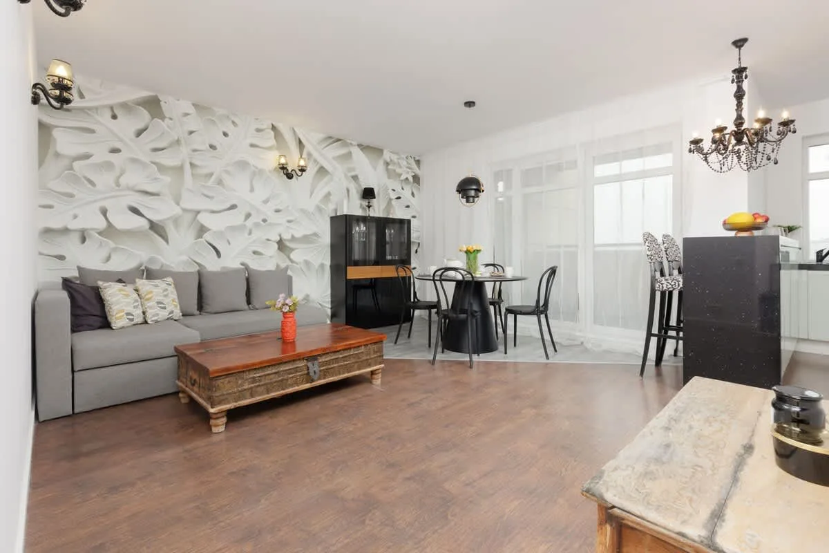 A spacious living area with a gray sofa, decorative wall art, and a rustic coffee table.