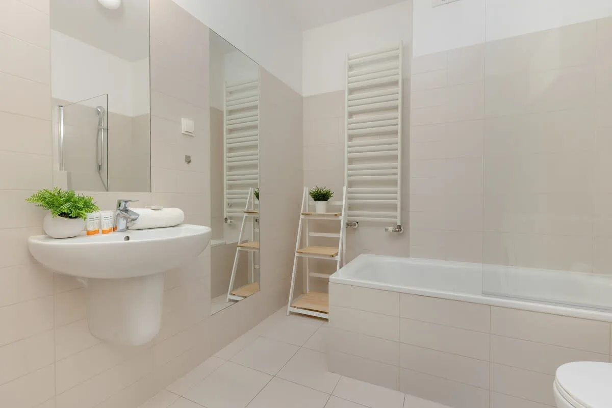 Another view of the bathroom showing a white sink and large mirror, enhancing the feeling of space and cleanliness.