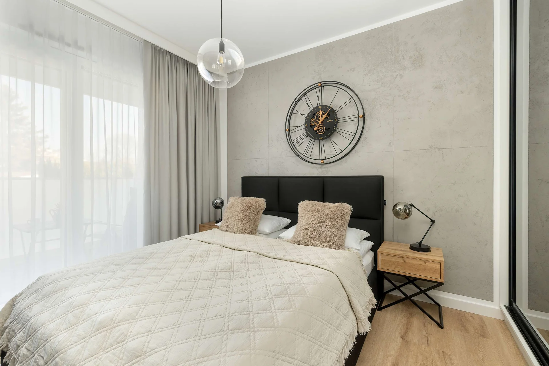 A cozy bedroom featuring a double bed with decorative pillows and a soft beige throw, set against a textured wall with  elegant mirrors.