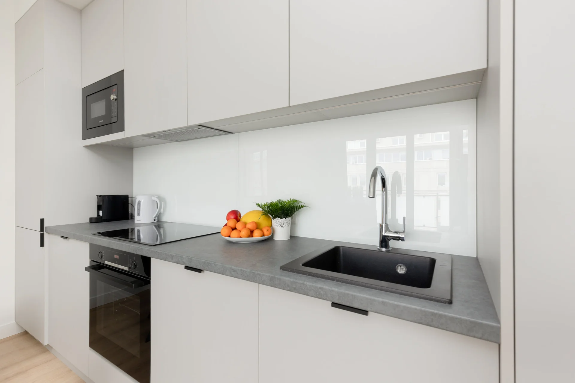 A modern kitchen with white cabinets and a black countertop, equipped with appliances.