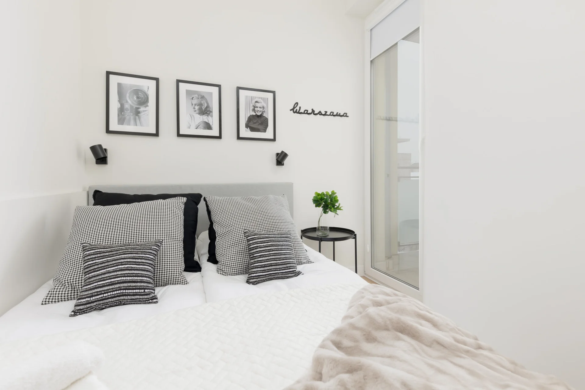 A bedroom featuring a neatly made bed with white linens and decorative pillows.