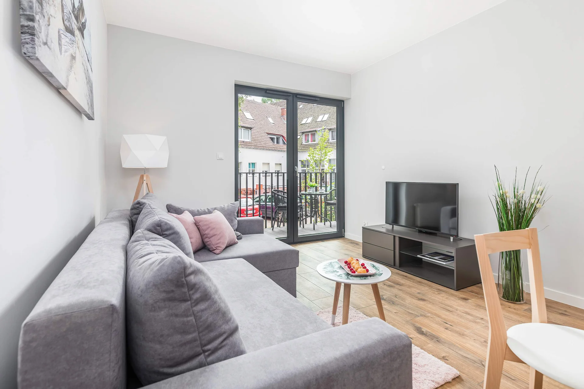 The bright living room with a fold-out grey sofa allows for relaxation and rest, while evening entertainment is provided by a flat-screen TV.