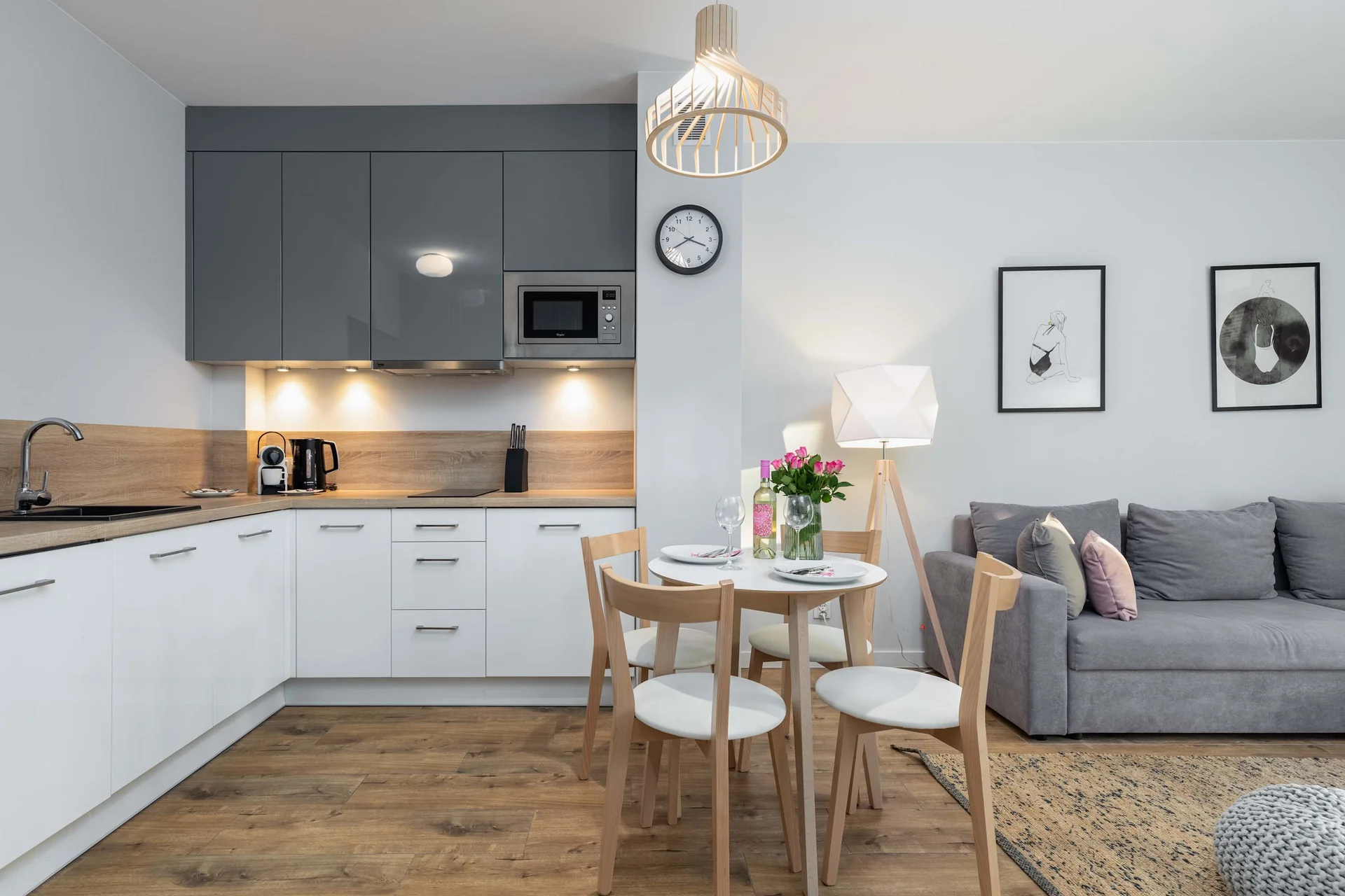 The round dining table with a white top coherently connects the cozy part of the living room with the functional kitchenette.
