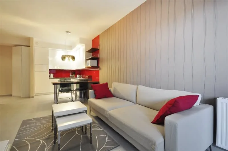 A modern studio with a cozy seating area, a double bed, and warm lighting for a welcoming ambiance.