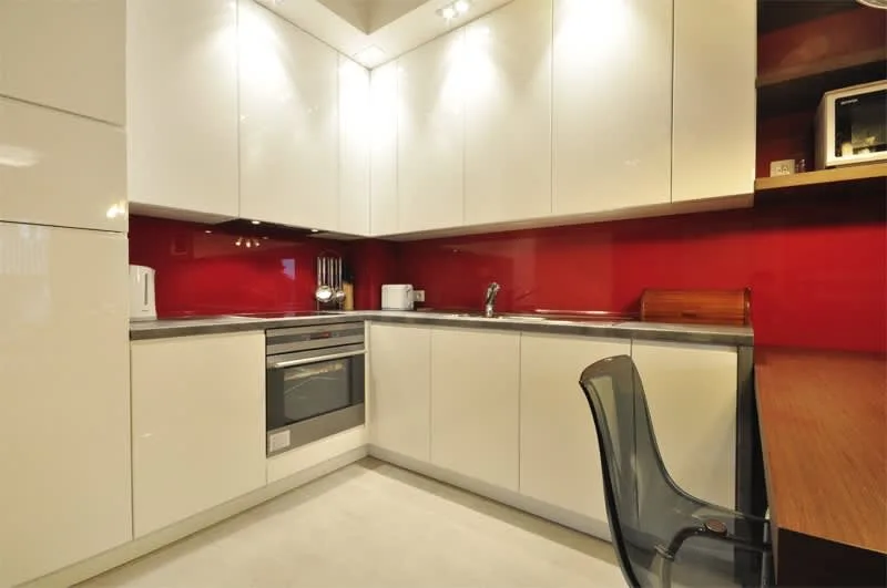 A sleek, red-accented kitchenette with modern appliances and plenty of counter space.
