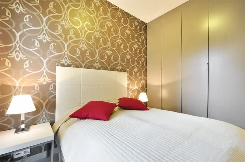 The double bed is complemented by elegant wallpaper and bedside lamps, creating a comfortable and stylish corner.