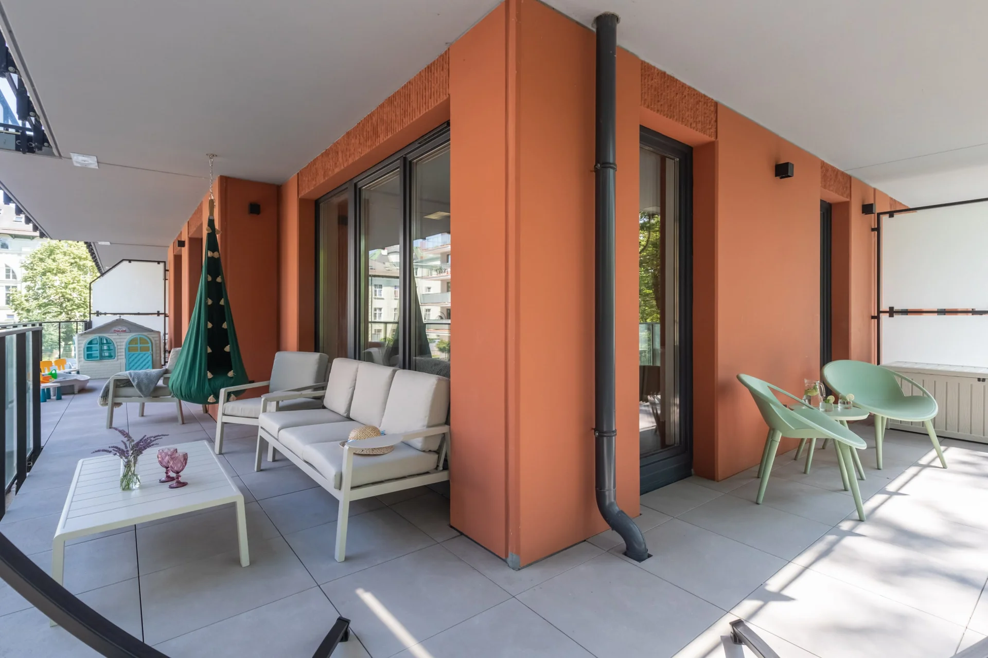 Outdoor patio with modern furniture and a vibrant orange facade, perfect for relaxing.