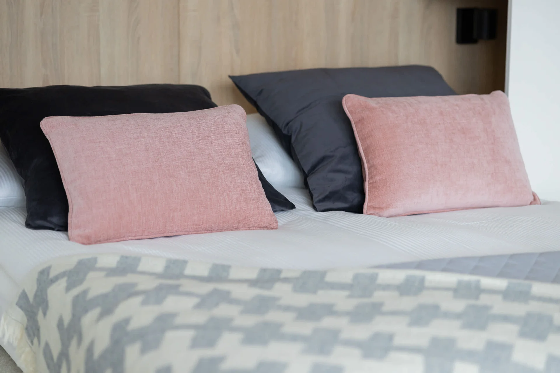 A close-up of the bed with plush pillows in shades of pink and gray, adding a touch of elegance to the space.