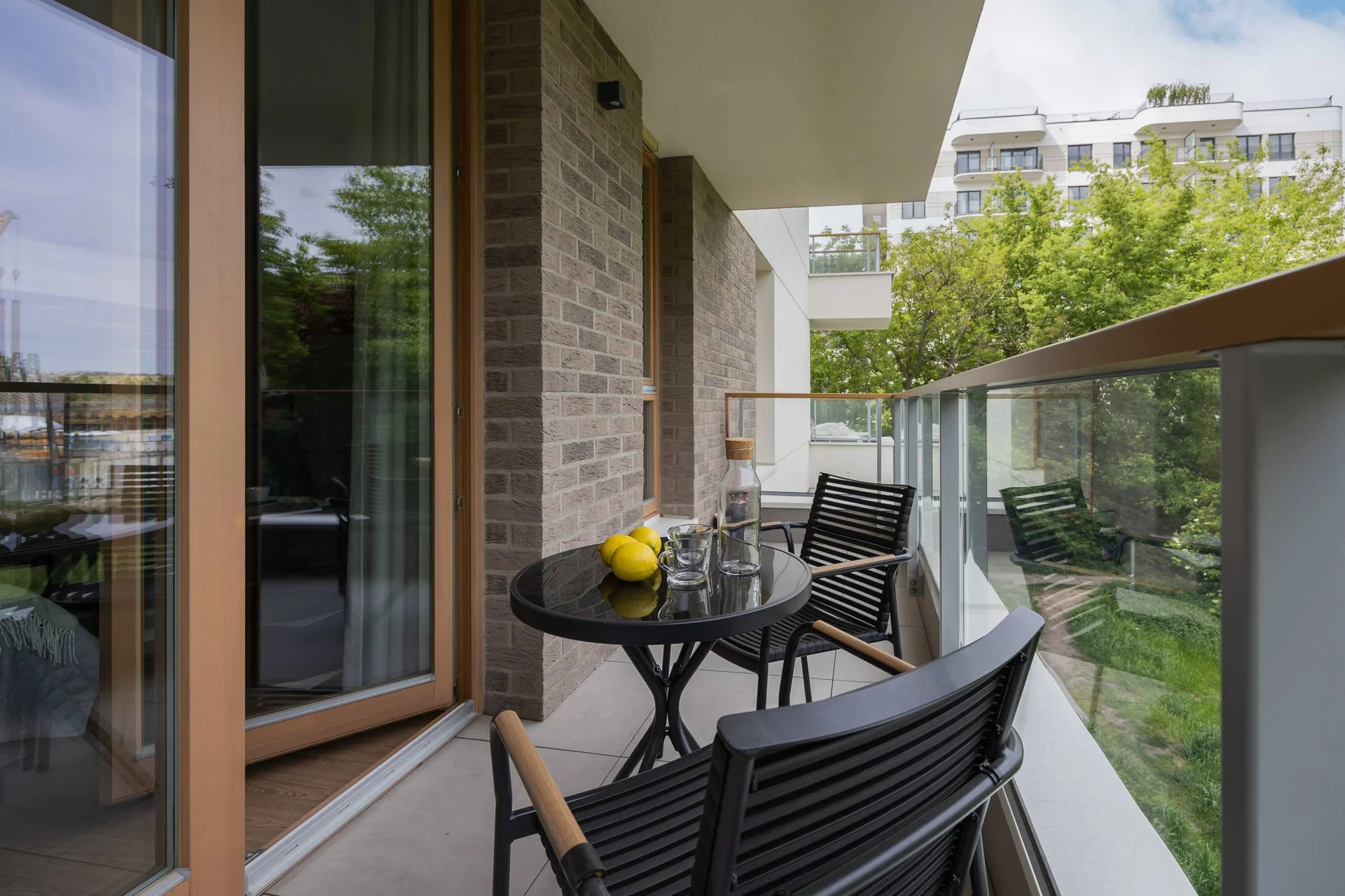 A balcony equipped with rattan furniture and surrounded by lush plants, offering a tranquil outdoor retreat.