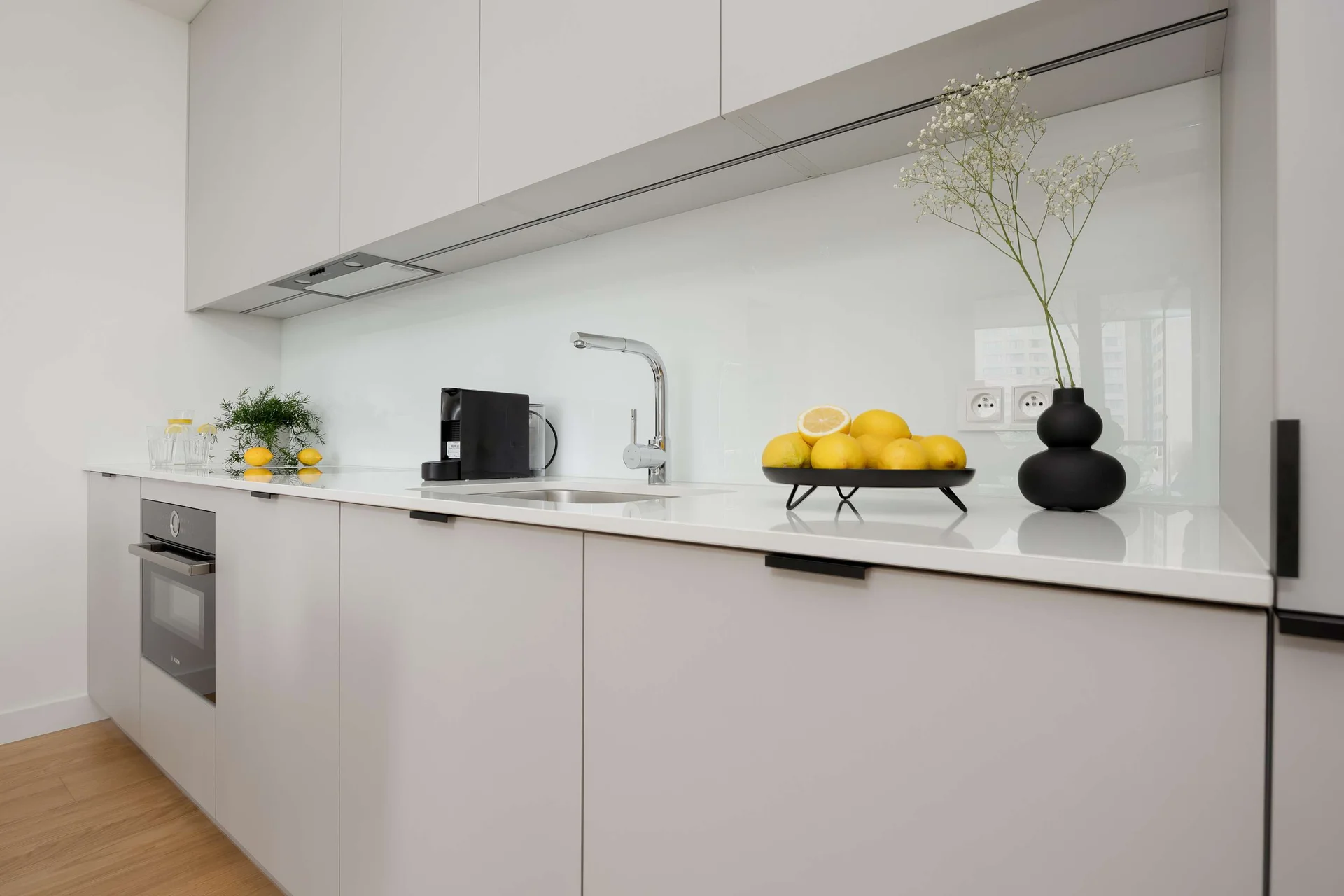 Modern white kitchen with built-in appliances and a light countertop.