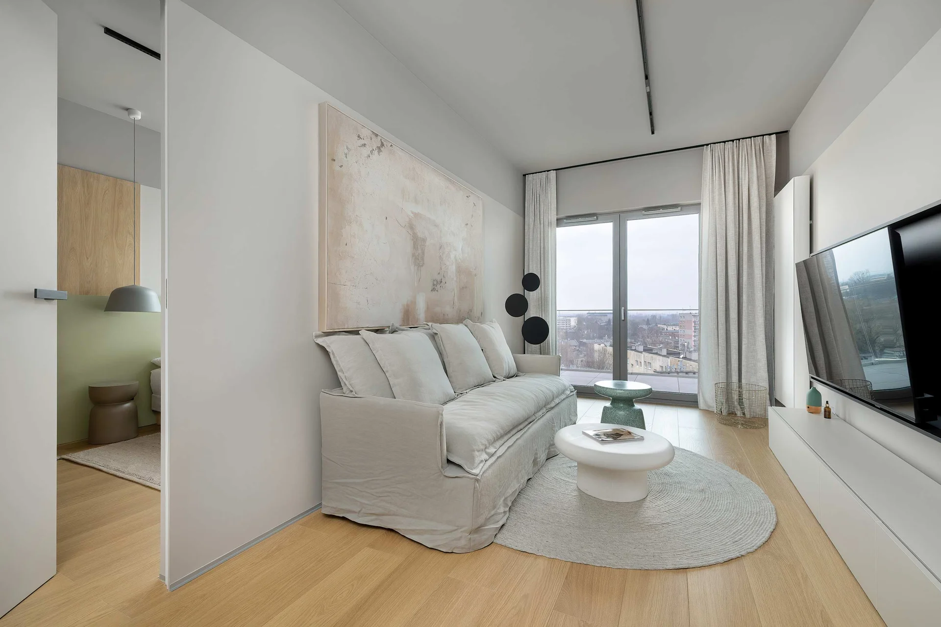 A contemporary living room with a soft sofa, round coffee table, and subtle decorative elements. Neutral colors and soft textures create a calm and inviting ambiance.