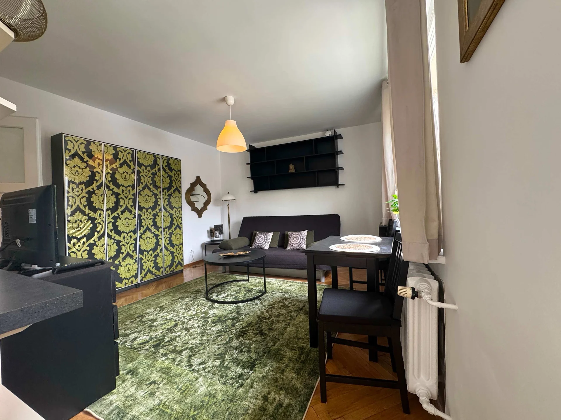 The living room is viewed from the opposite side, highlighting the sofa, coffee table, and artistic accent wall. The layout is practical and inviting for everyday use.