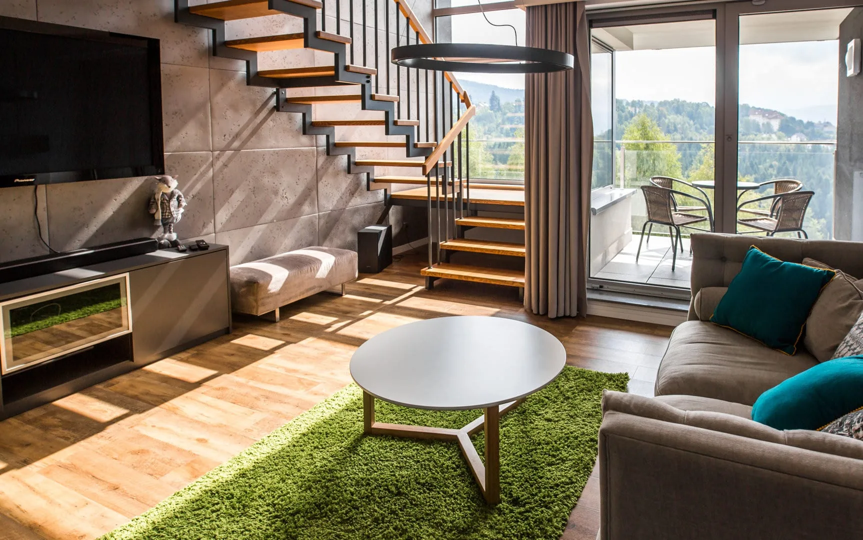 The bright living room with large windows and access to the balcony creates a space where you can enjoy natural light and views from the very morning.