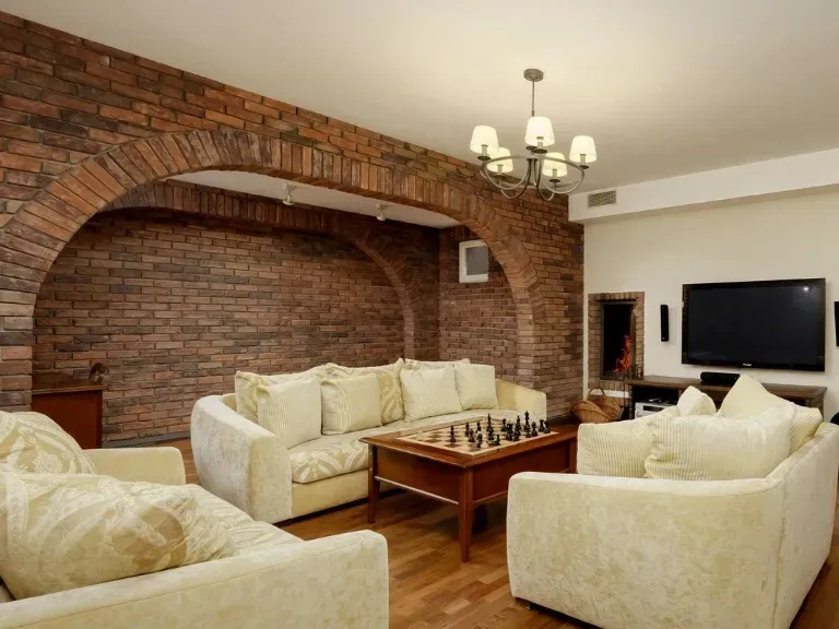 Apartament w Konstancin-Jeziorna, jasne sofy, ceglane ściany, szachy, TV