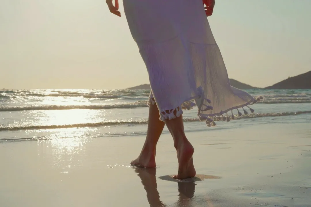 Kobieta idąca po plaży w kierunku morza, zbliżenie na stopy